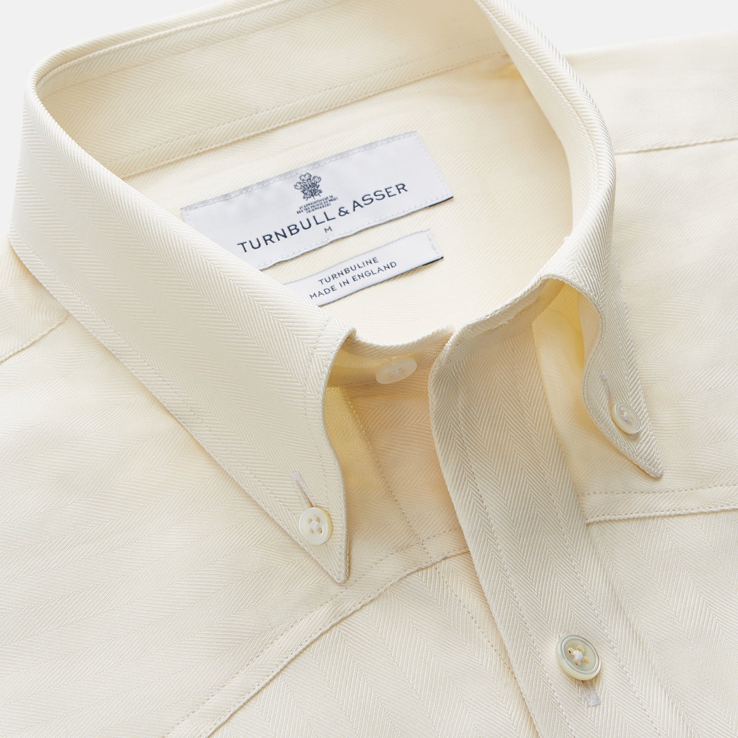 View 2 of product The Turnbull & Asser Cream Weekend Fit Larkin Shirt features a Dorset collar, 3-button cuffs, and two button-flap chest pockets in soft herringbone cotton, displayed flat on a white background.