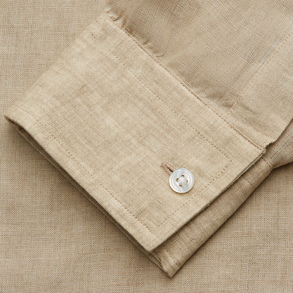 A man with a bald head and trimmed beard wears the Turnbull & Asser Beige Weekend Fit Linen Blake Shirt with stand collar and 1-button cuffs, standing calmly against a matching beige background.