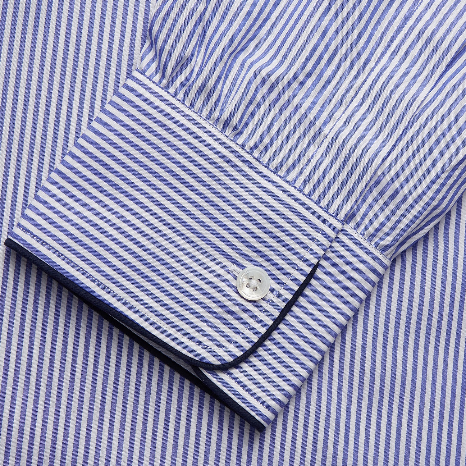View 4 of product The Turnbull & Asser Blue Bengal Stripe Piped Cotton Nightshirt features long sleeves, a pointed collar, dark-trimmed pocket, curved hem, button details, and cuffed sleeves for an elegant look.