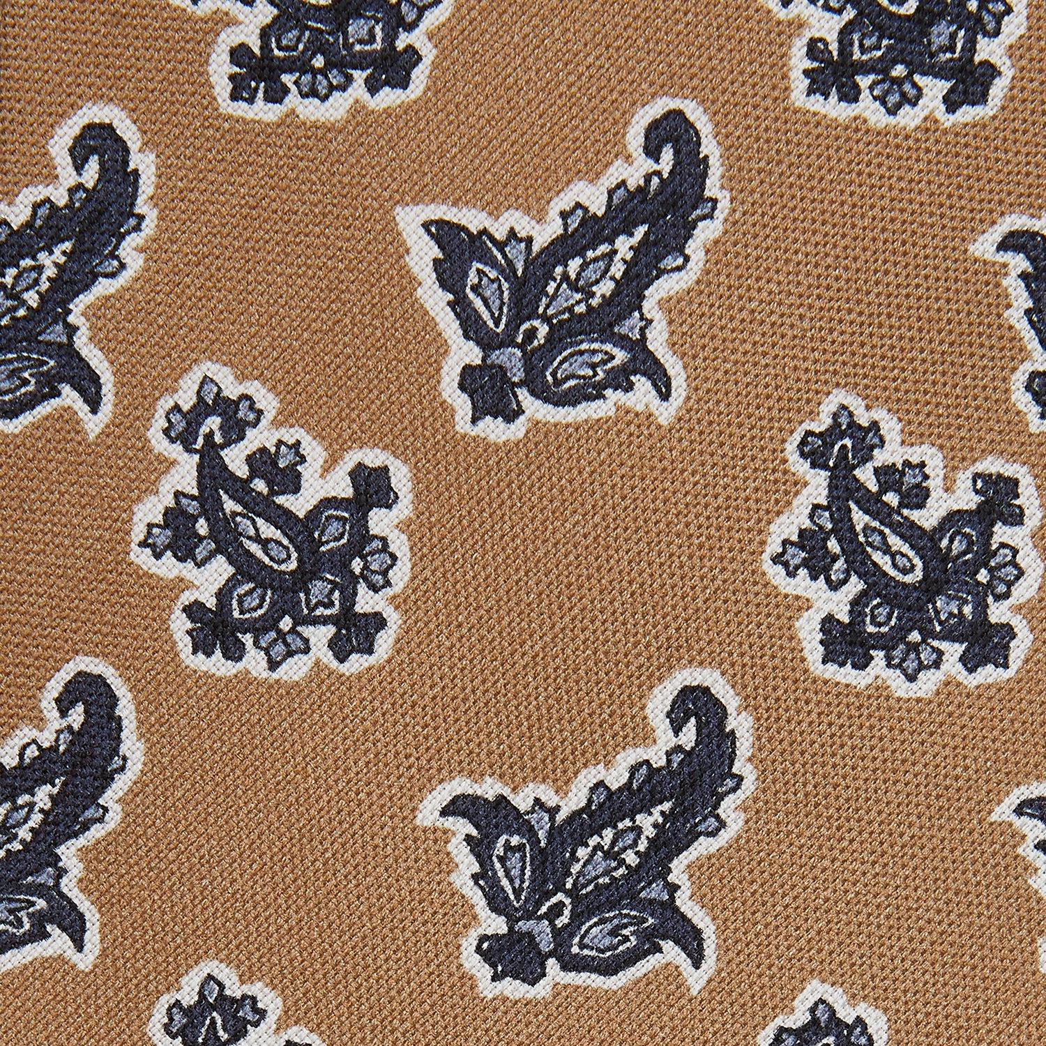 View 2 of product The Turnbull & Asser Toffee Paisley Floral Cotton Silk Blend Tie features a rolled-up design with dark blue and white paisley motifs on a tan background.