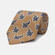 The Turnbull & Asser Toffee Paisley Floral Cotton Silk Blend Tie features a rolled-up design with dark blue and white paisley motifs on a tan background.