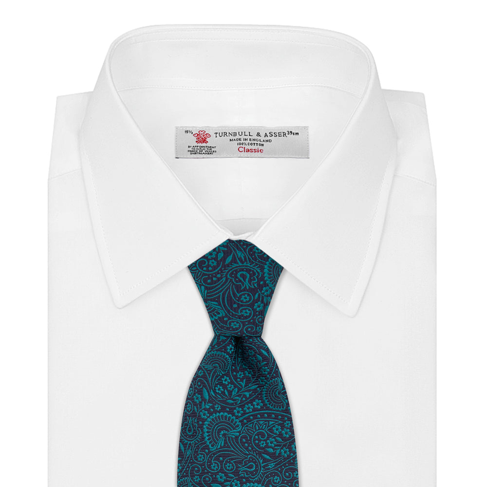 The Turnbull & Asser Green and Navy Tonal Paisley Silk Tie is an elegant men's accessory, featuring a rolled-up design with an intricate paisley pattern, shown on a white background.