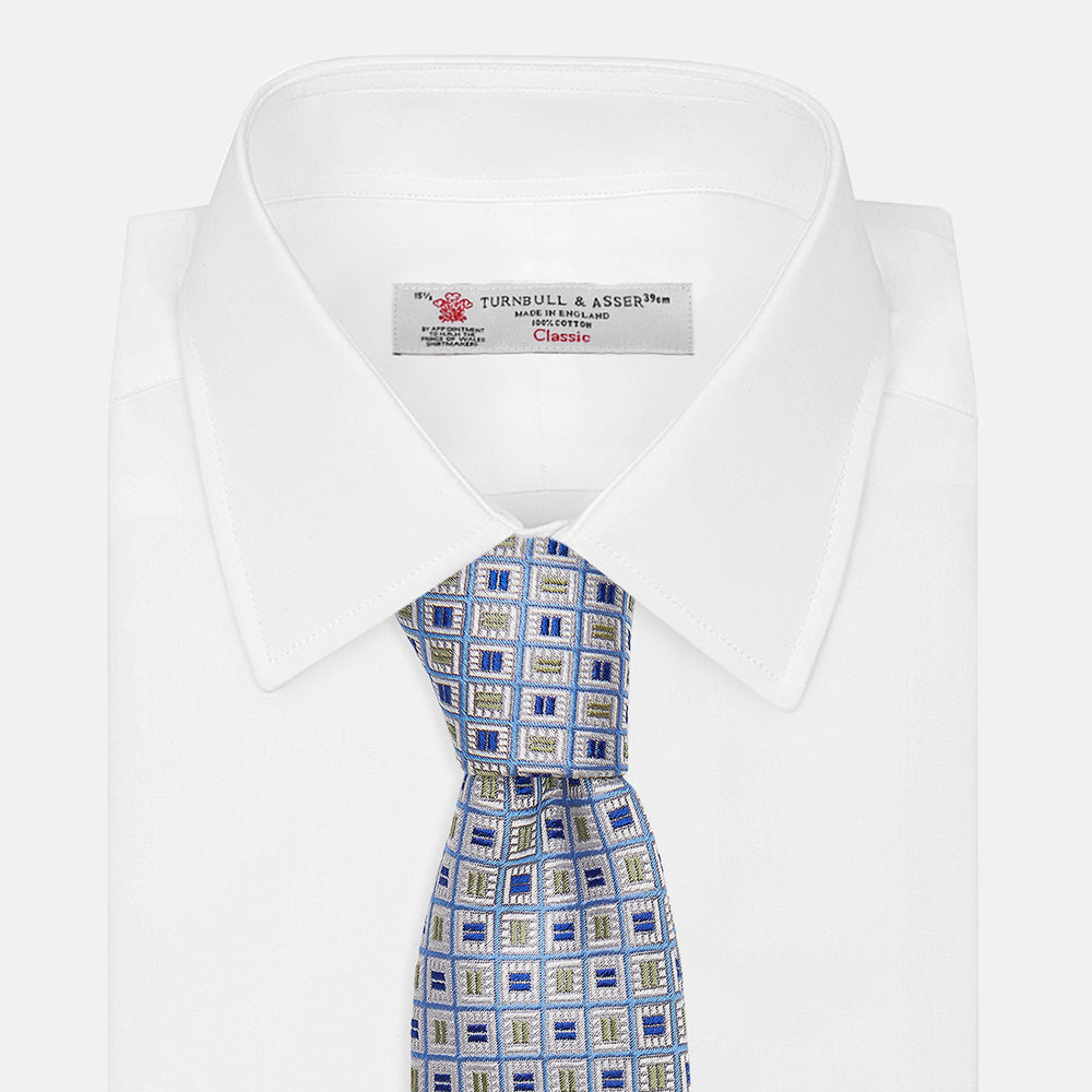 A Turnbull & Asser Blue and Yellow Geometric Silk Jacquard Tie is shown rolled up on a plain light background.