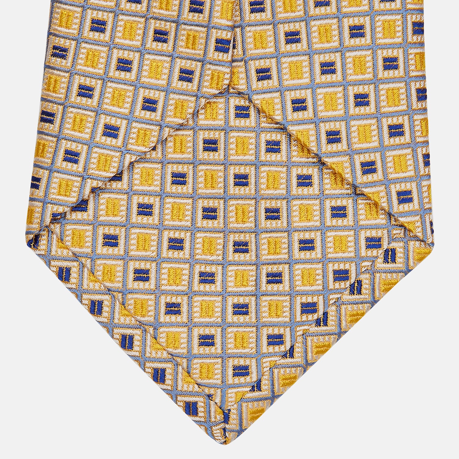 View 3 of product The Turnbull & Asser Yellow and Navy Geometric Silk Jacquard Tie features a striking square pattern on a light background, ideal for formal occasions, shown rolled up against a plain white surface.