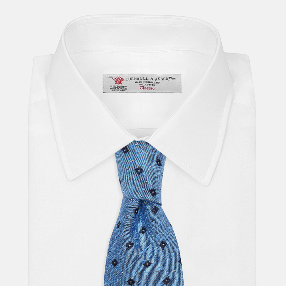The Turnbull & Asser Dark Blue Fine Square Slub Silk Tie, featuring an elegant square pattern and subtle texture, is shown rolled-up against a plain white background.