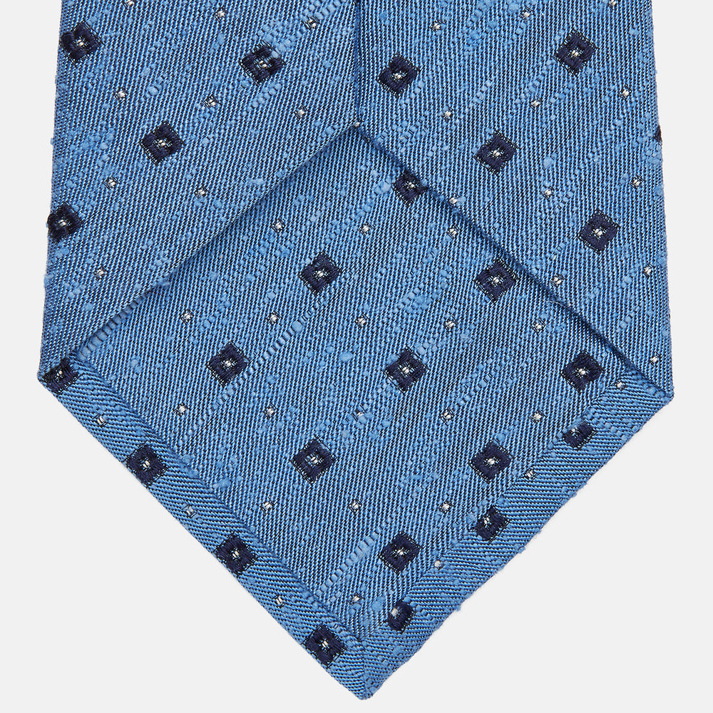 The Turnbull & Asser Dark Blue Fine Square Slub Silk Tie, featuring an elegant square pattern and subtle texture, is shown rolled-up against a plain white background.