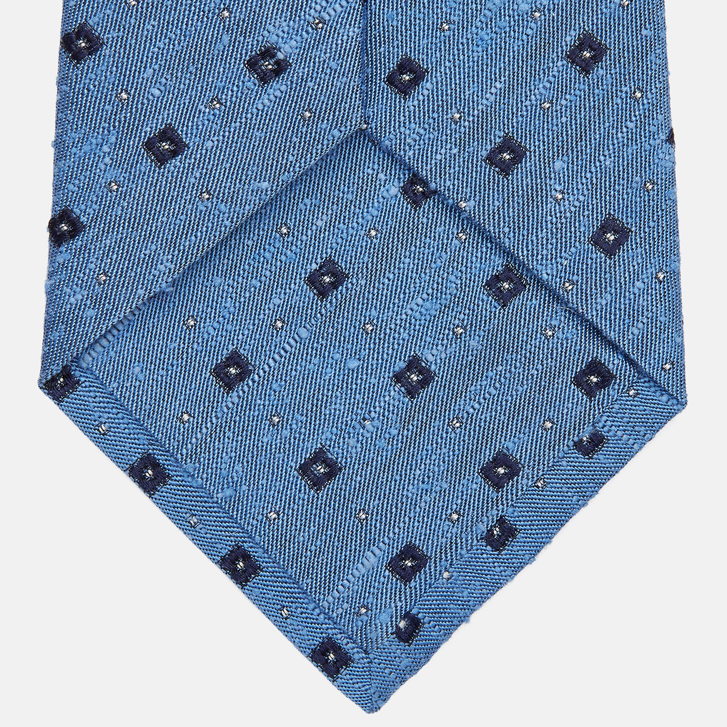 View 3 of product The Turnbull & Asser Dark Blue Fine Square Slub Silk Tie, featuring an elegant square pattern and subtle texture, is shown rolled-up against a plain white background.