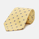 The Turnbull & Asser Yellow Fine Square Slub Silk Tie features a soft yellow jacquard with a subtle texture, decorated with a repeating blue and white diamond pattern, shown rolled up on a plain white background.