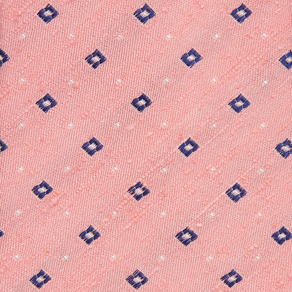 The Turnbull & Asser Pink Fine Square Slub Silk Tie features a pastel pink silk jacquard with blue and white geometric squares, shown rolled up on a plain white background.