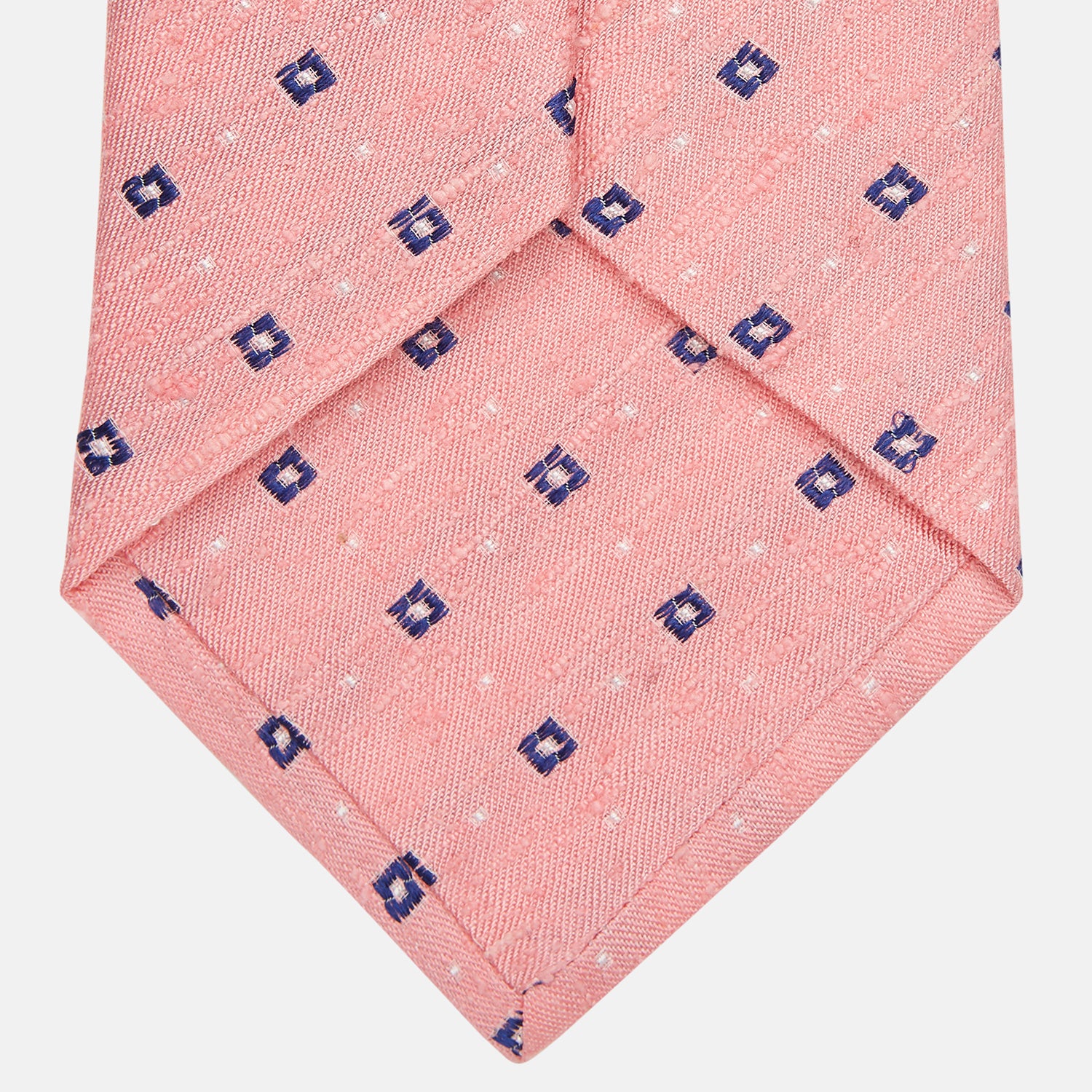 View 3 of product The Turnbull & Asser Pink Fine Square Slub Silk Tie features a pastel pink silk jacquard with blue and white geometric squares, shown rolled up on a plain white background.