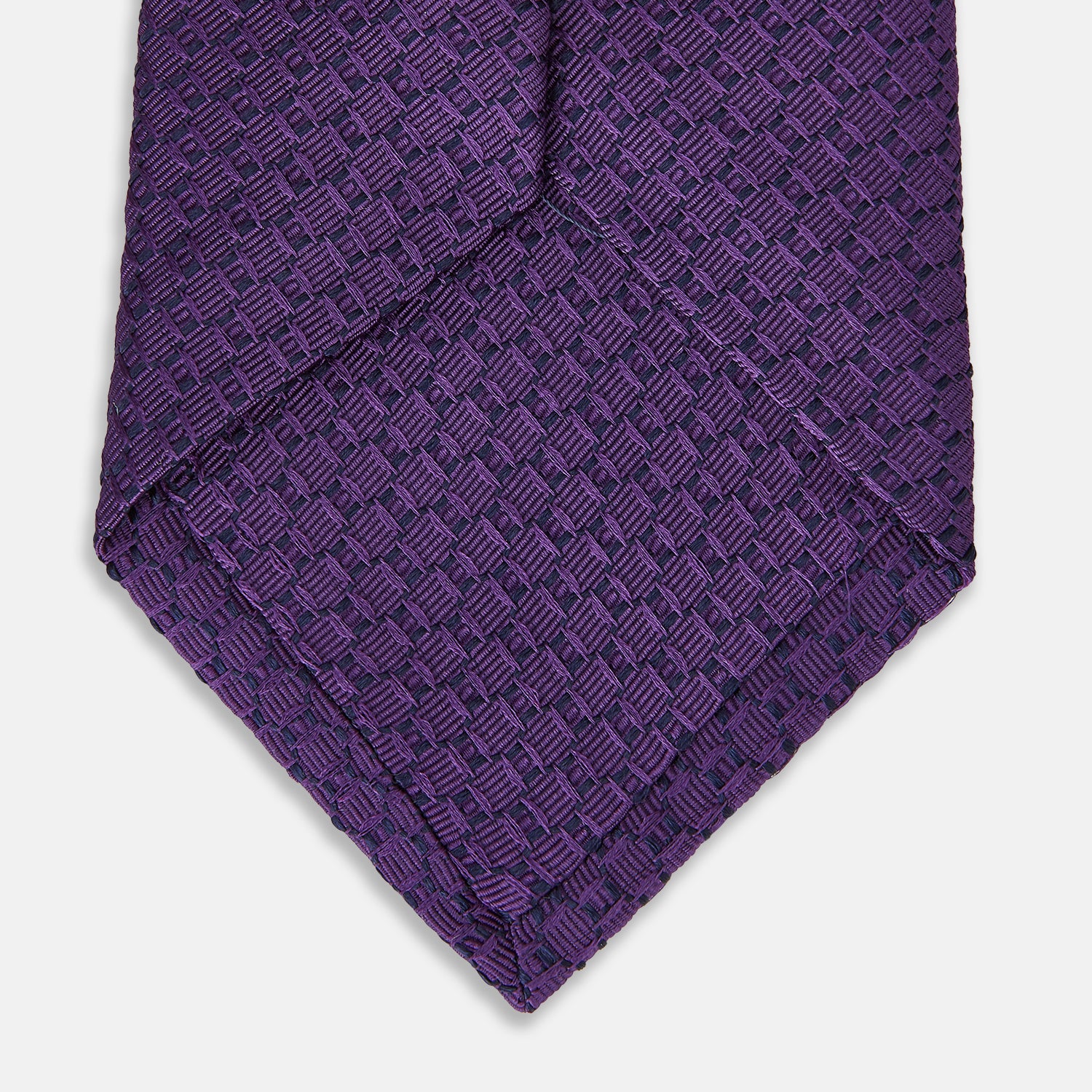 View 4 of product The Turnbull & Asser Purple Abstract Tonal Silk Jacquard Tie, featuring a textured geometric pattern, is shown rolled up against a white background—an ideal choice to elevate any formal outfit.