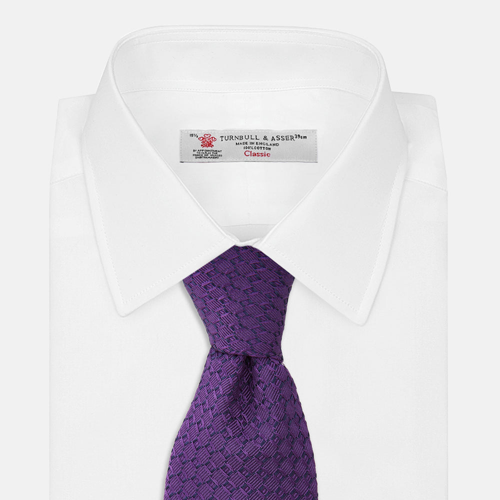 The Turnbull & Asser Purple Abstract Tonal Silk Jacquard Tie, featuring a textured geometric pattern, is shown rolled up against a white background—an ideal choice to elevate any formal outfit.
