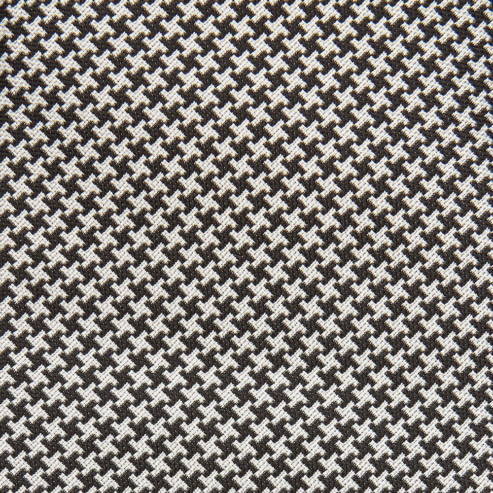 The Turnbull & Asser Fine Puppytooth Monochrome Silk Tie, in classic black and white, features a refined pattern and is shown rolled on a plain white background—ideal for enhancing any formal outfit.
