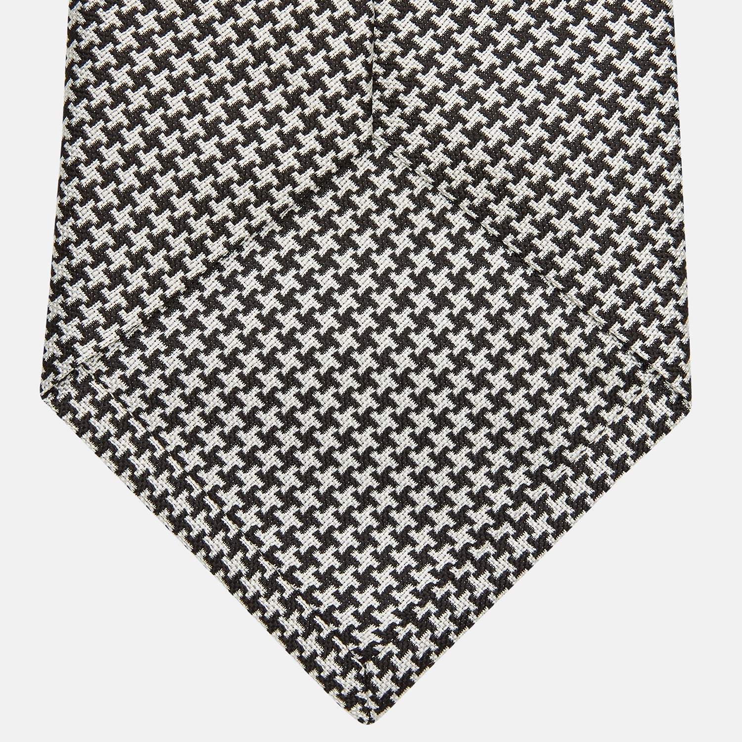 View 3 of product The Turnbull & Asser Fine Puppytooth Monochrome Silk Tie, in classic black and white, features a refined pattern and is shown rolled on a plain white background—ideal for enhancing any formal outfit.