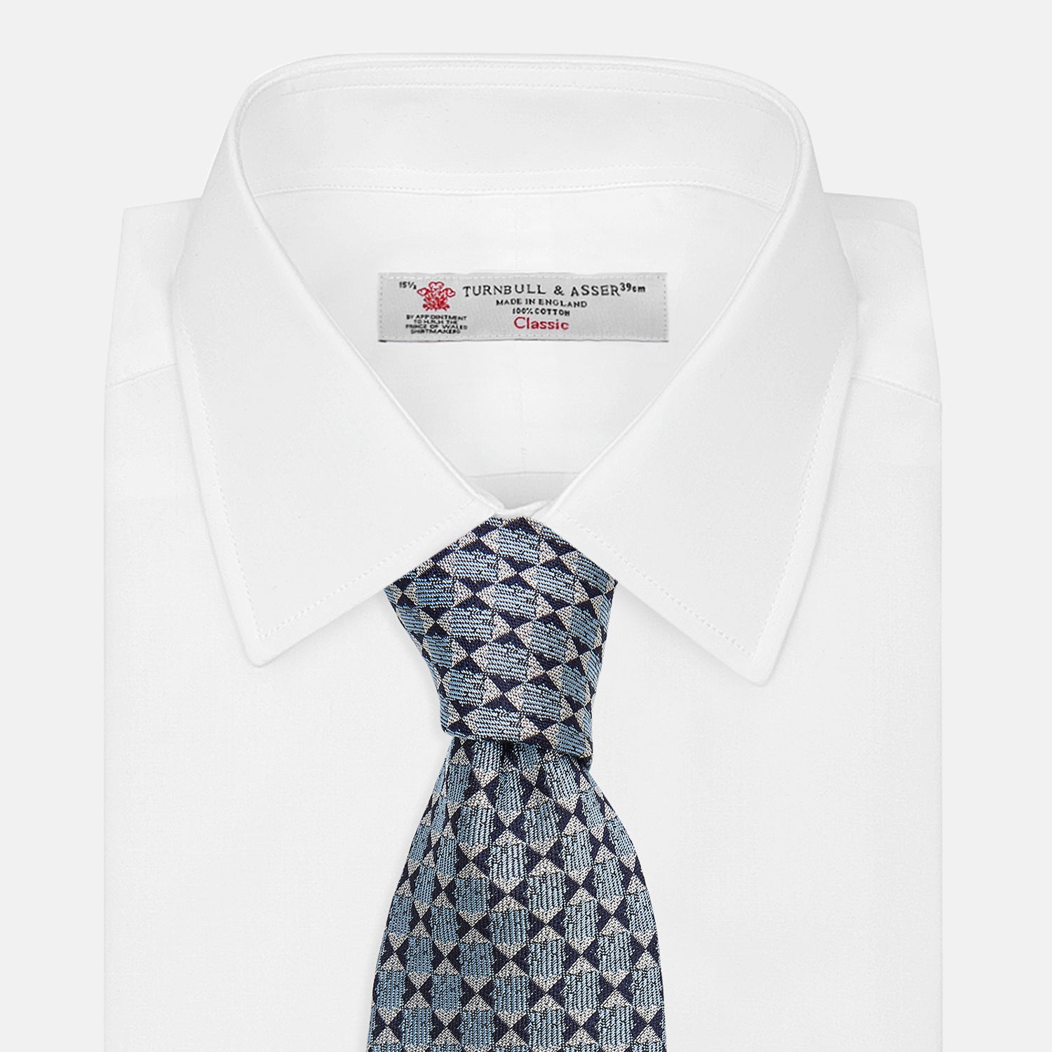 View 4 of product The Chambray Blue Graphic Floral Silk Jacquard Tie by Turnbull & Asser features a modern floral pattern in silk, shown rolled up against a plain white background.