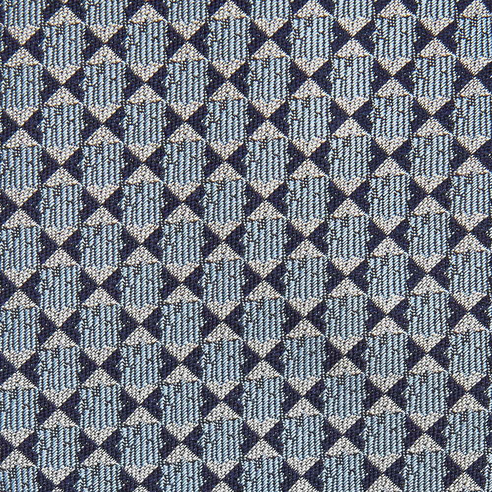 The Chambray Blue Graphic Floral Silk Jacquard Tie by Turnbull & Asser features a modern floral pattern in silk, shown rolled up against a plain white background.