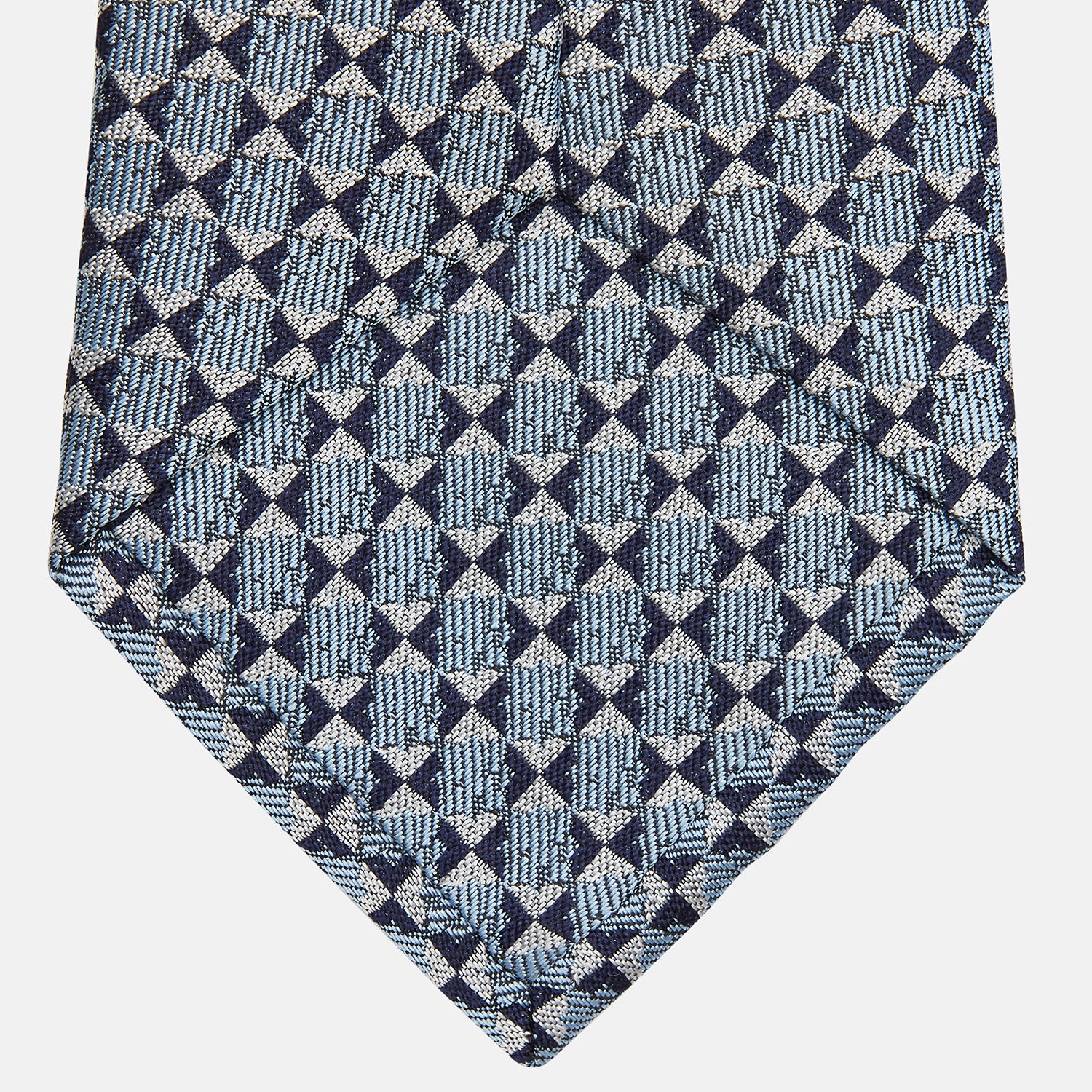 View 3 of product The Chambray Blue Graphic Floral Silk Jacquard Tie by Turnbull & Asser features a modern floral pattern in silk, shown rolled up against a plain white background.
