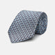 The Chambray Blue Graphic Floral Silk Jacquard Tie by Turnbull & Asser features a modern floral pattern in silk, shown rolled up against a plain white background.
