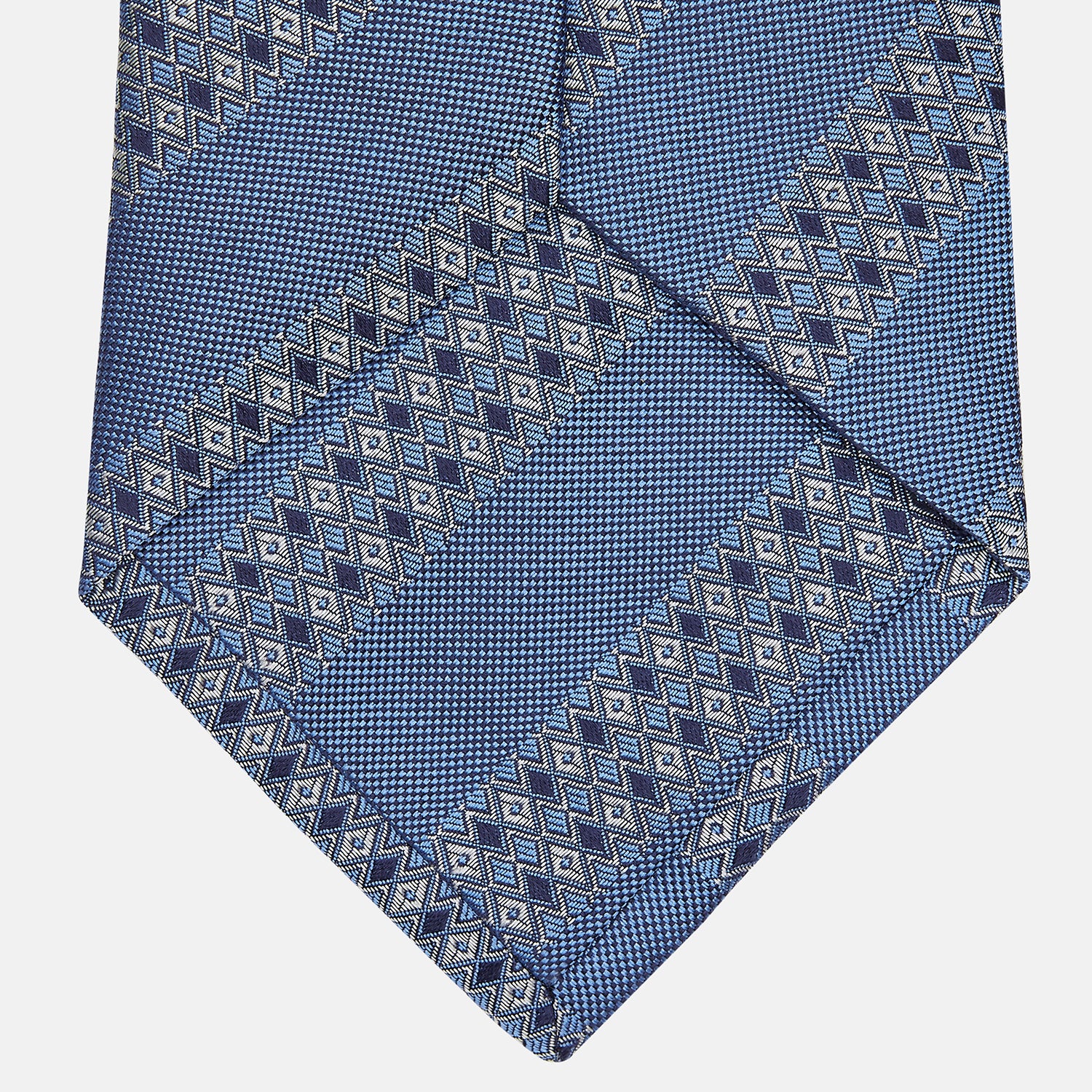 View 3 of product The Turnbull & Asser Dark Blue Baroque Stripe Silk Jacquard Tie, featuring elegant baroque stripes, is displayed rolled up on a white background.