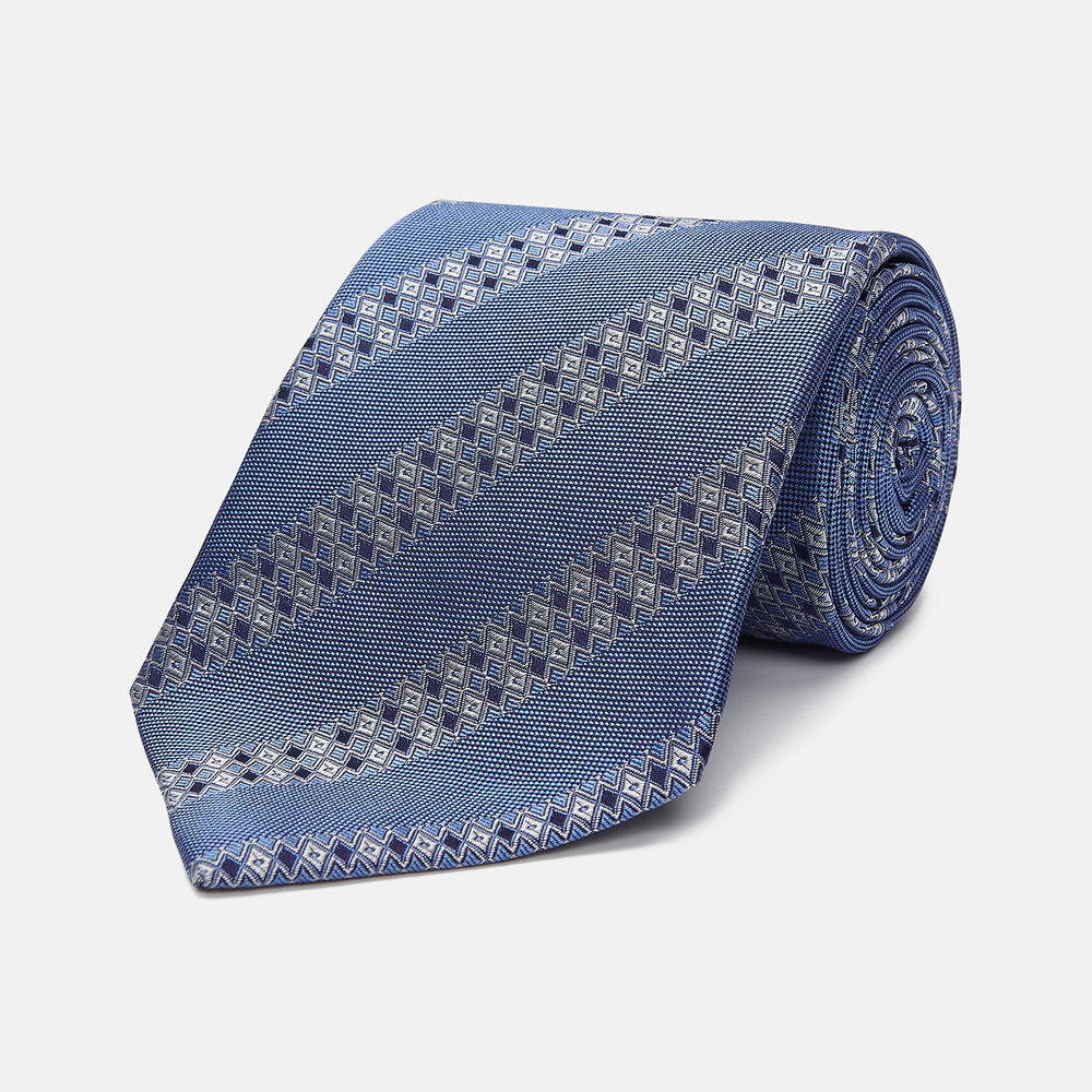 The Turnbull & Asser Dark Blue Baroque Stripe Silk Jacquard Tie, featuring elegant baroque stripes, is displayed rolled up on a white background.