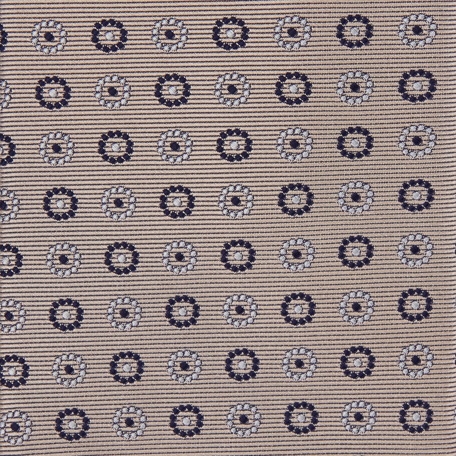 View 3 of product The Turnbull & Asser Beige Spheric Emblem Tie, a formalwear essential, features a neat roll and a repeating pattern of navy and white circular floral motifs on pastel beige.