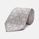 The Turnbull & Asser Toffee and Powder Blue Circle Jacquard Silk Tie, featuring an interlocking circular pattern, is rolled up and displayed on a plain white background.