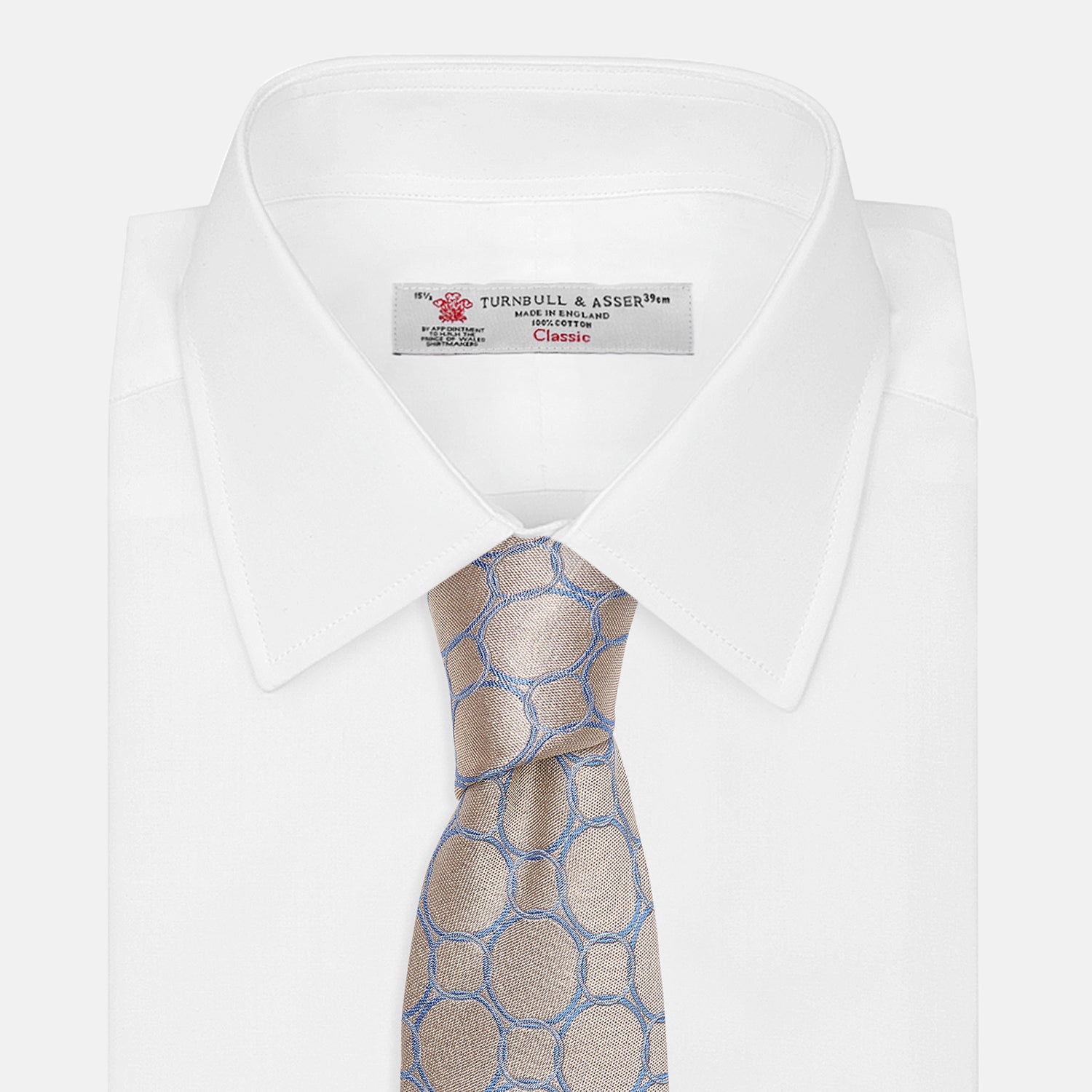 View 4 of product The Turnbull & Asser Toffee and Powder Blue Circle Jacquard Silk Tie, featuring an interlocking circular pattern, is rolled up and displayed on a plain white background.