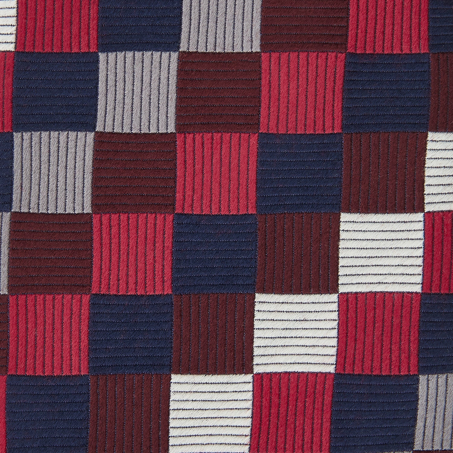 View 3 of product The Burgundy Checkerboard Silk Jacquard Tie by Turnbull & Asser features a bold autumnal pattern in red, navy blue, brown, gray, burgundy, and white squares, shown rolled on a plain white background.
