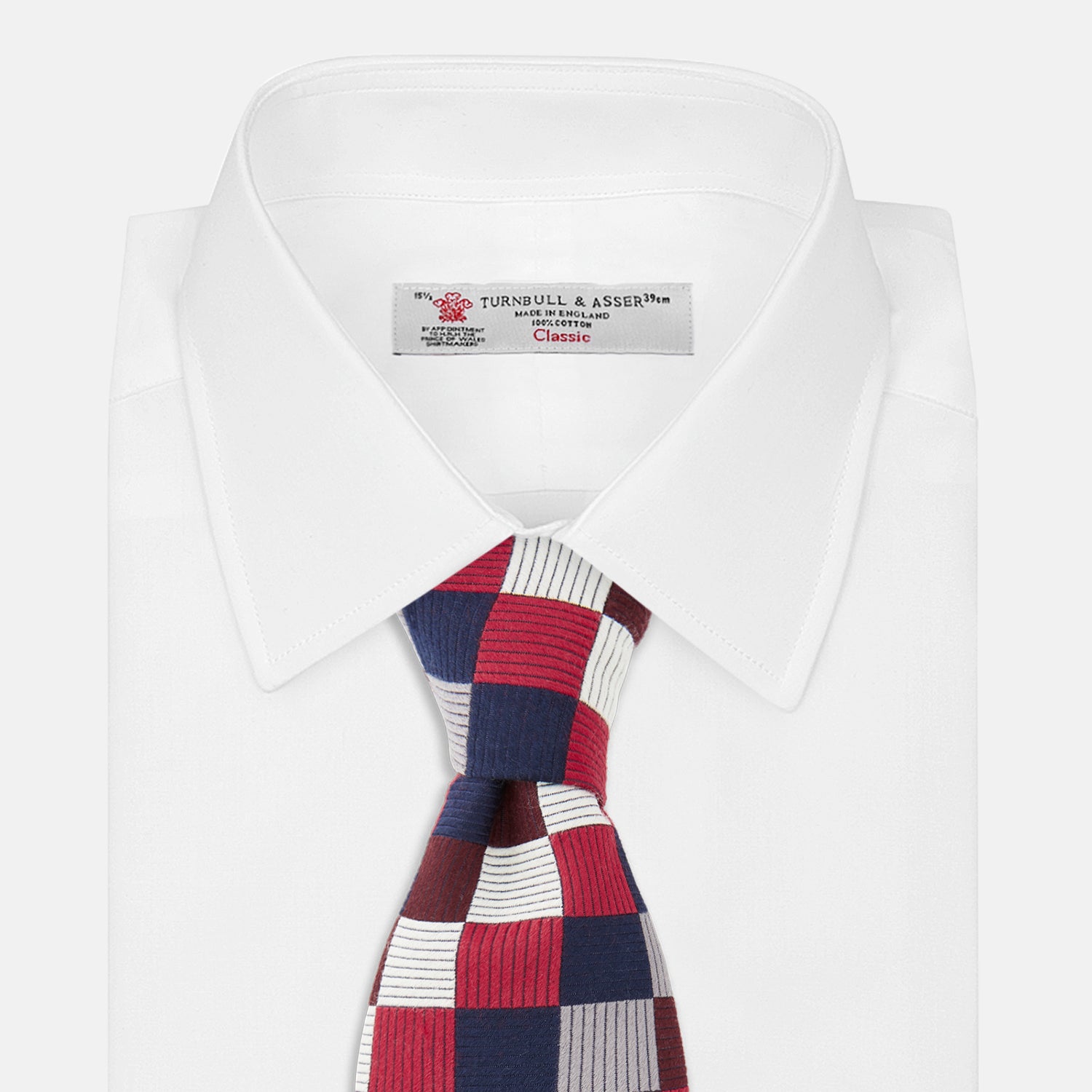 View 2 of product The Burgundy Checkerboard Silk Jacquard Tie by Turnbull & Asser features a bold autumnal pattern in red, navy blue, brown, gray, burgundy, and white squares, shown rolled on a plain white background.