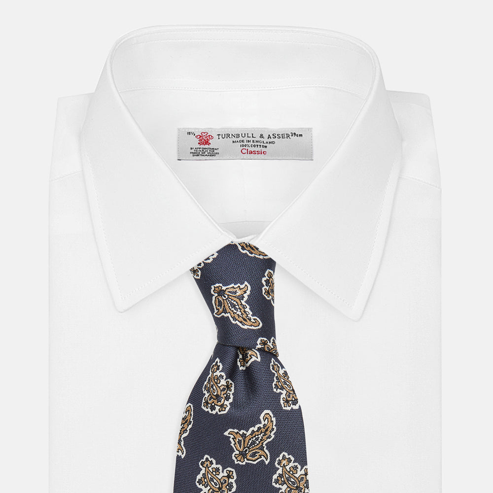 The Turnbull & Asser Navy Paisley Floral Cotton Silk Blend Tie features beige and light blue paisley motifs on navy, with one end rolled.