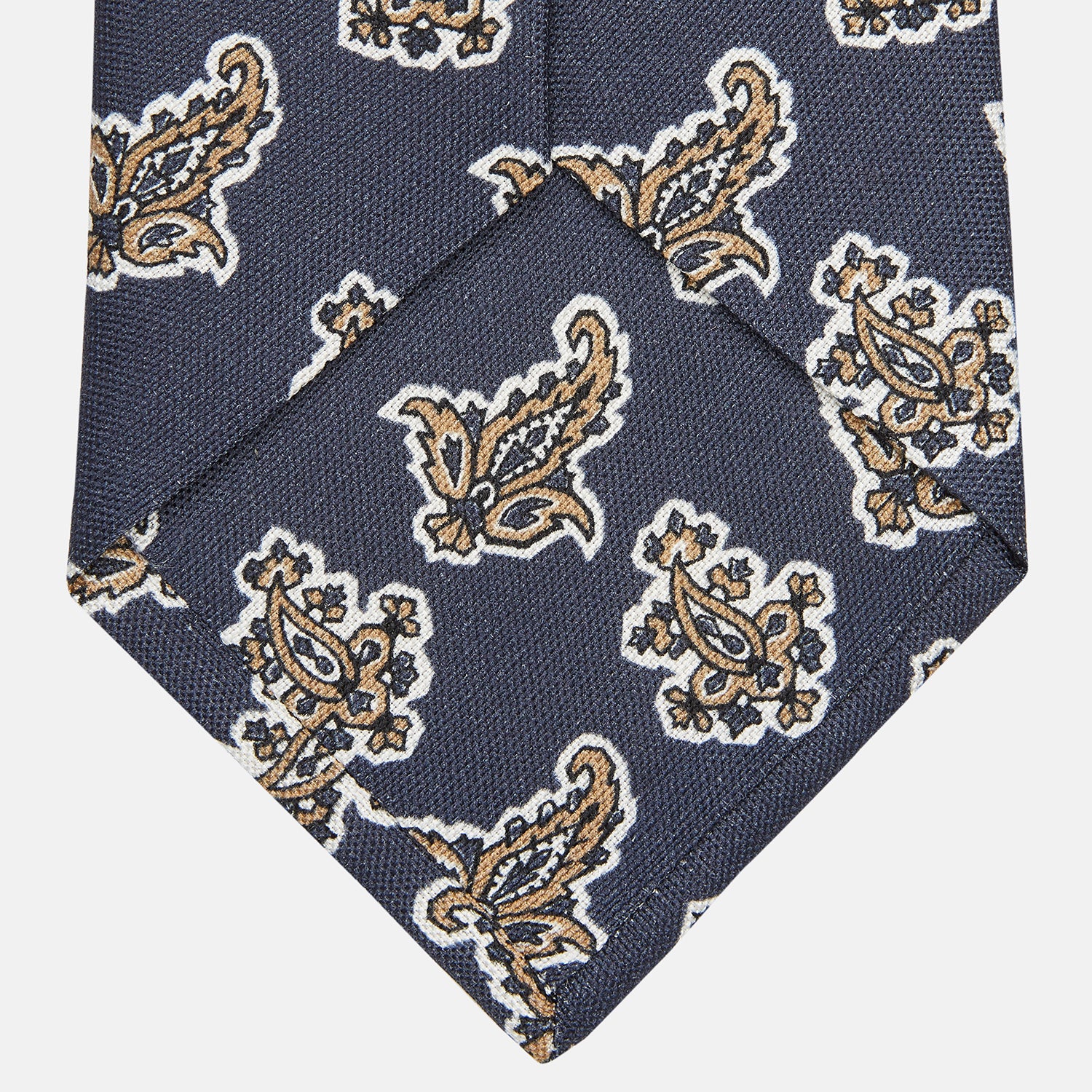 View 4 of product The Turnbull & Asser Navy Paisley Floral Cotton Silk Blend Tie features beige and light blue paisley motifs on navy, with one end rolled.