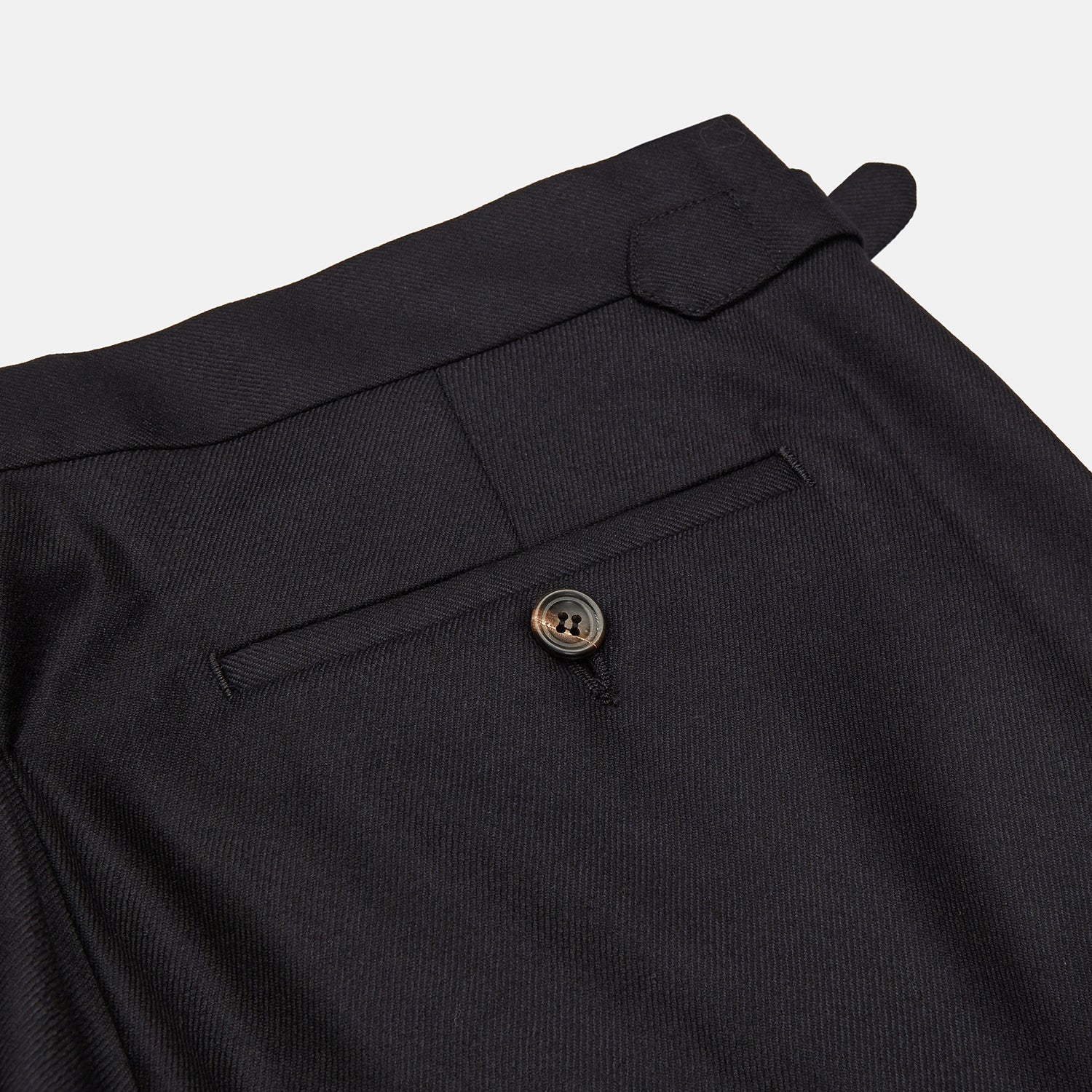 View 2 of product A pair of navy Escorial wool trousers by Turnbull & Asser, featuring a tailored style, straight-leg fit, front crease, belt loops, side pockets, and metal buckle details on the waistband, shown against a white background.