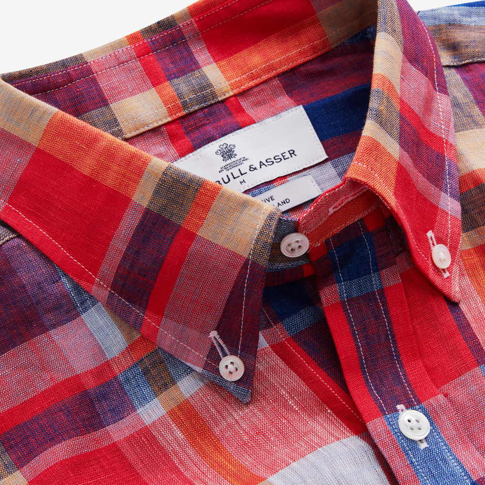 The Turnbull & Asser Red Madras Check Weekend Fit Short Sleeve Linen Shirt features a Dorset collar, white buttons, and a red, blue, white, and beige plaid pattern. Shown on a plain white background.