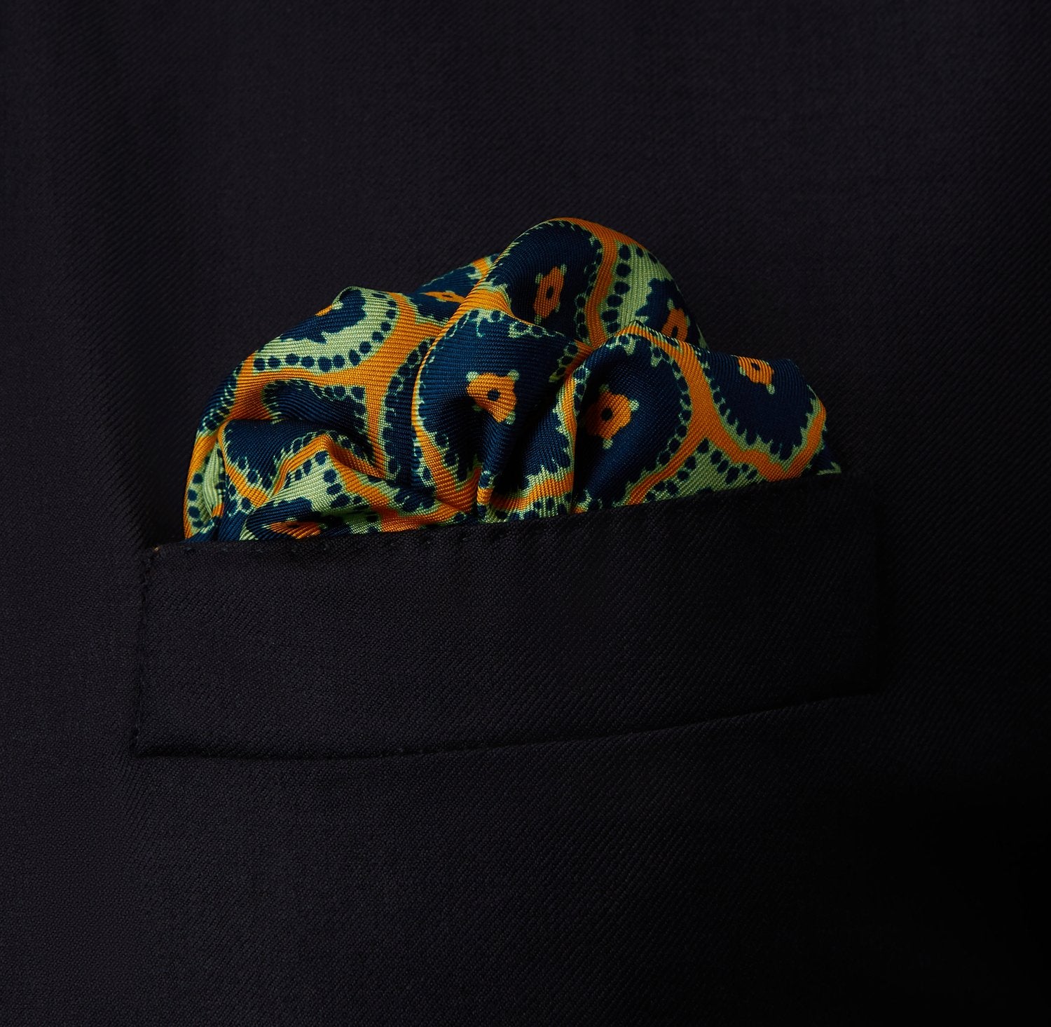 View 2 of product The Yellow Medallion Print Silk Pocket Square by Turnbull & Asser features blue hexagons with ochre yellow centers on a dark blue background, bordered by a dotted ochre yellow frame—a stylish accessory for any suit.