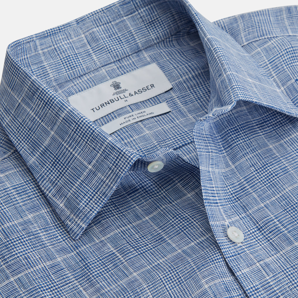 The Indigo Linen Glen Check Weekend Fit Shirt with Derby Collar by Turnbull & Asser is a light blue, long-sleeve checked linen shirt, featuring a subtle white plaid pattern and shown against a plain white background.