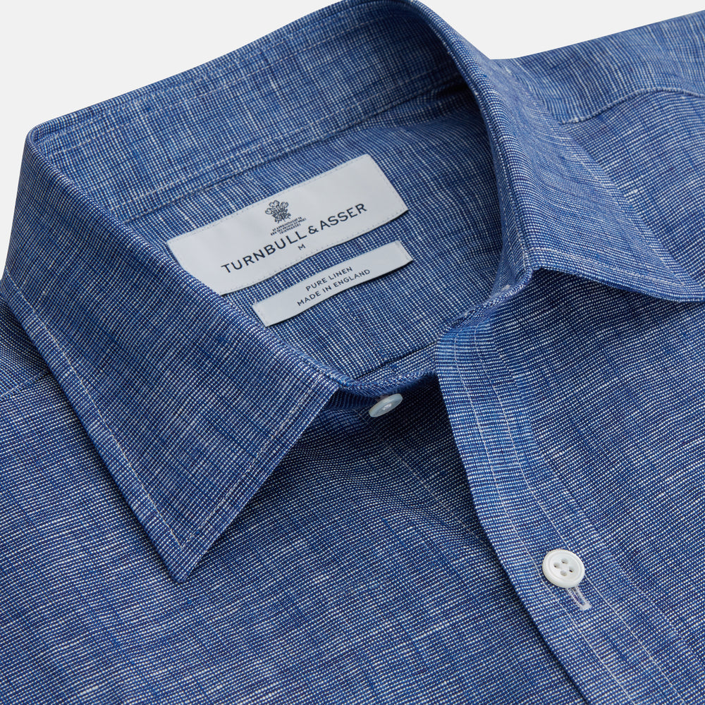 The Indigo Linen Weekend Fit Shirt with Derby Collar by Turnbull & Asser, shown flat on a white background, features long sleeves, white buttons, and buttoned cuffs—ideal for pairing with a classic suit or for casual wear.