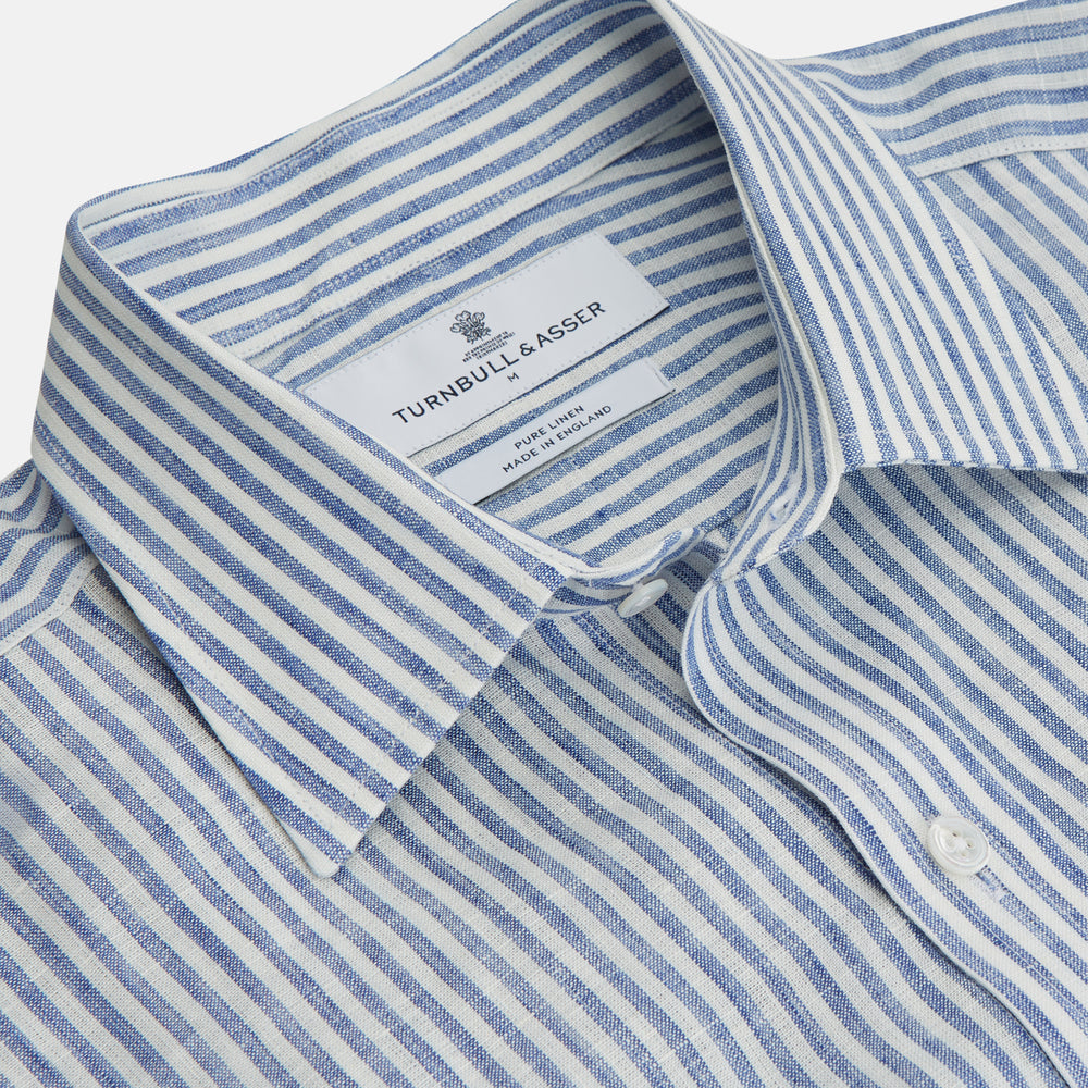 The Turnbull & Asser Sky Blue Linen Stripe Weekend Fit Shirt features blue and white vertical stripes, a Derby collar, and buttoned cuffs—ideal for pairing with classic cotton suits or other Weekend Fit shirts.