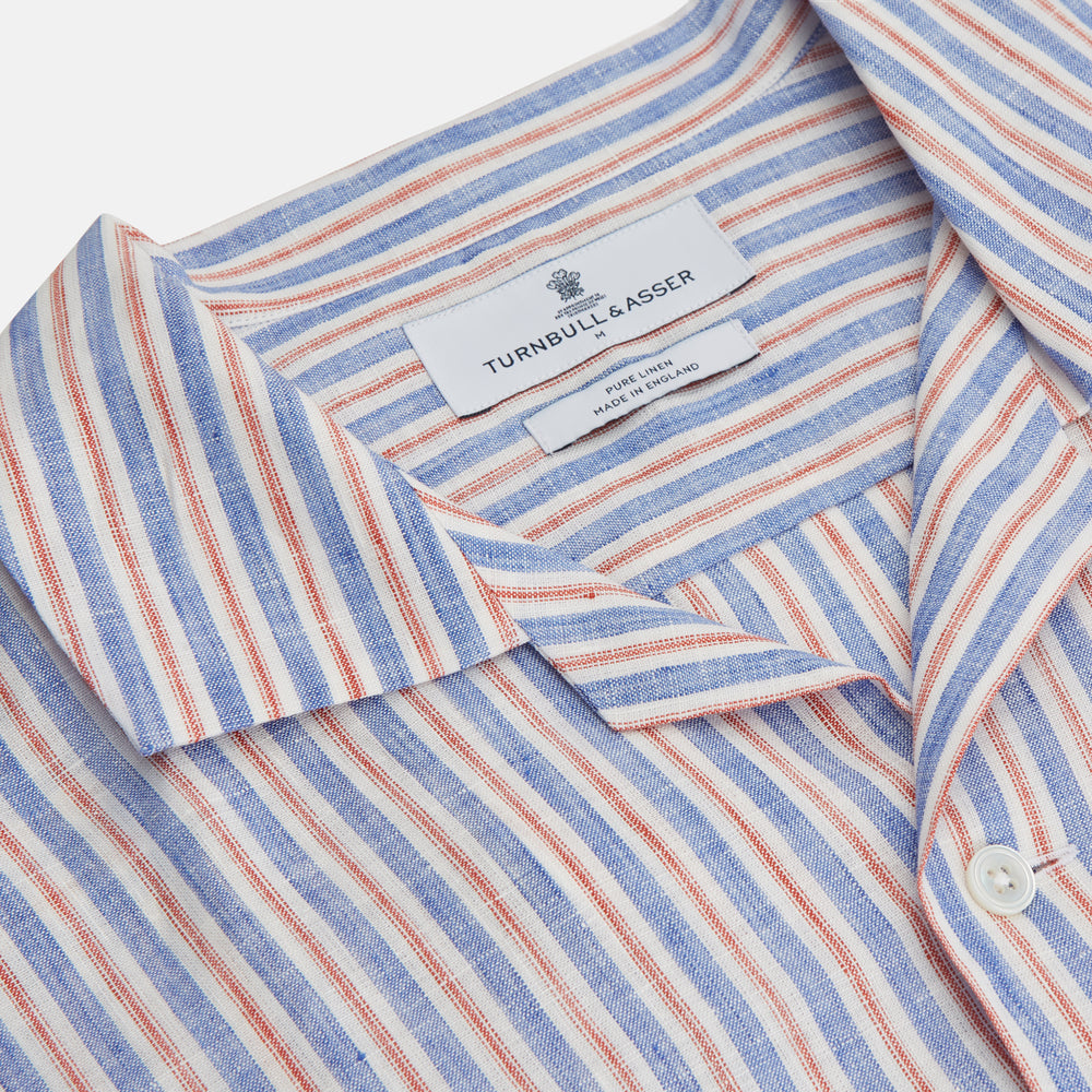 The Turnbull & Asser Blue and Red Linen Stripe Holiday Fit Shirt features a revere collar, relaxed fit, and short sleeves—perfect resort wear with vertical blue, white, and light red stripes.