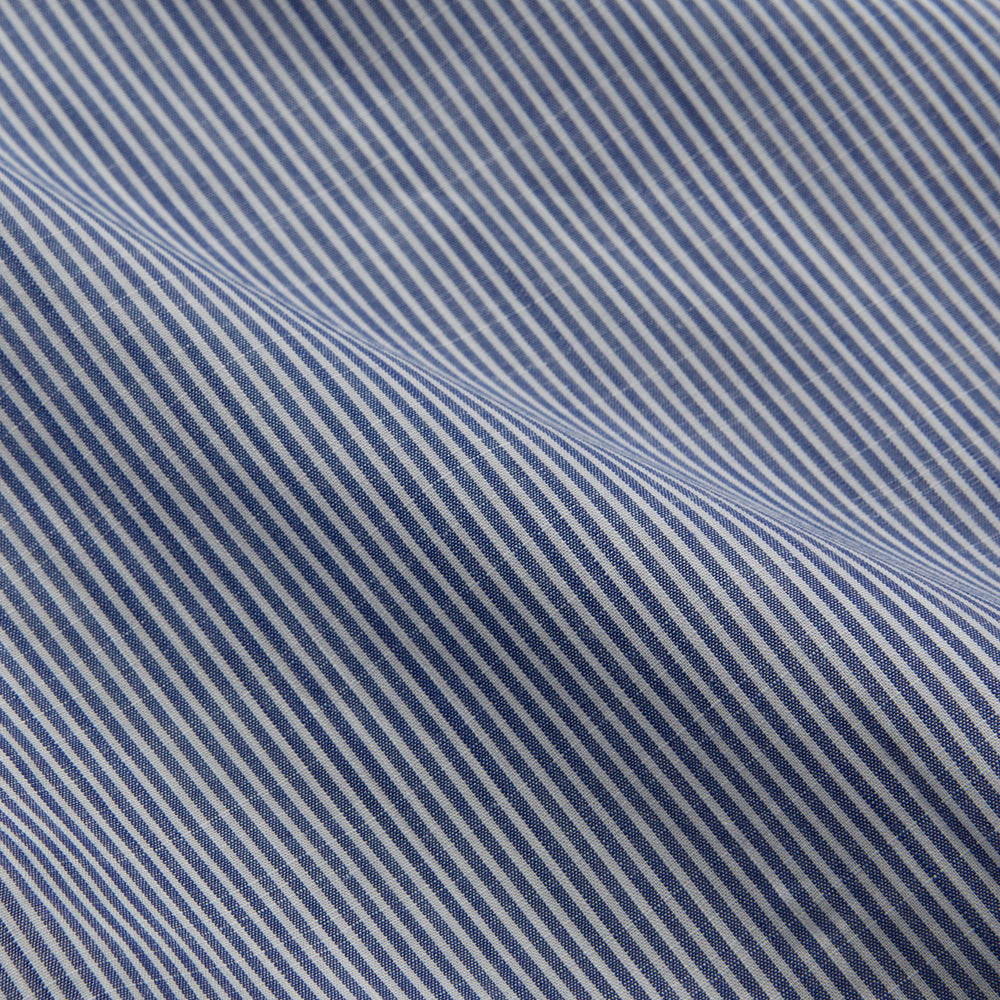 Turnbull & Asser’s Indigo Chambray Stripe Weekend Fit Shirt with Dorset collar features thin white pinstripes, two button-flap chest pockets, buttoned cuffs, and relaxed styling—presented flat on a white background.