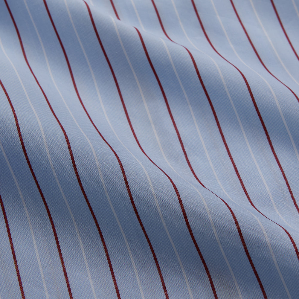 The Turnbull & Asser Burgundy Stripe Classic Pyjama Set features long sleeves, a button-up top with red piping, matching drawstring pants, and a traditional fit. Laid flat, it's luxury loungewear in signature burgundy stripes.