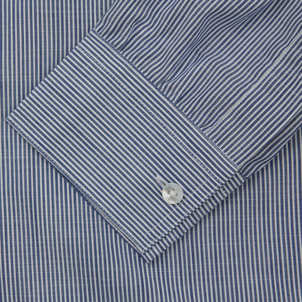 Turnbull & Asser’s Indigo Chambray Stripe Weekend Fit Shirt with Dorset collar features thin white pinstripes, two button-flap chest pockets, buttoned cuffs, and relaxed styling—presented flat on a white background.