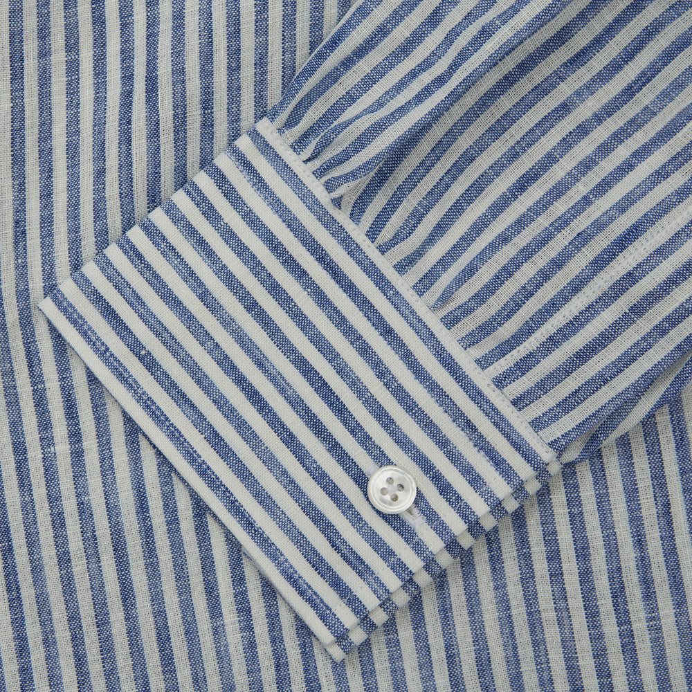 The Turnbull & Asser Sky Blue Linen Stripe Weekend Fit Shirt features blue and white vertical stripes, a Derby collar, and buttoned cuffs—ideal for pairing with classic cotton suits or other Weekend Fit shirts.