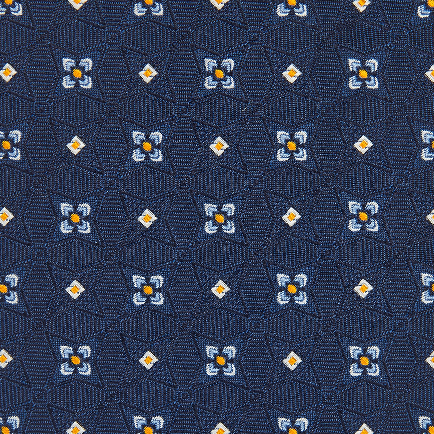 View 3 of product The Turnbull & Asser Navy Floral Emblem Tie displays a repeating pattern of small light blue, white, and yellow floral and diamond motifs, highlighting refined elegance, shown rolled up on a white background.