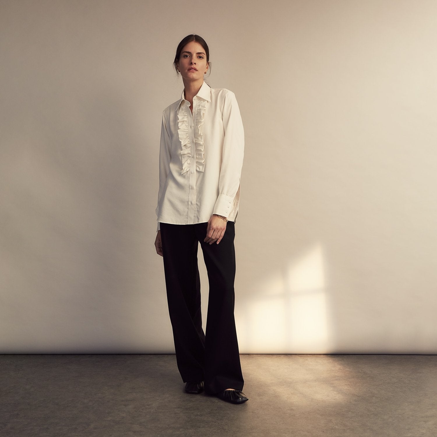 View 6 of product The Turnbull & Asser Turnbull and The Deck Cream Silk Romantic Shirt features long sleeves, a pointed collar, and elegant front ruffles, shown against a plain light gray background.