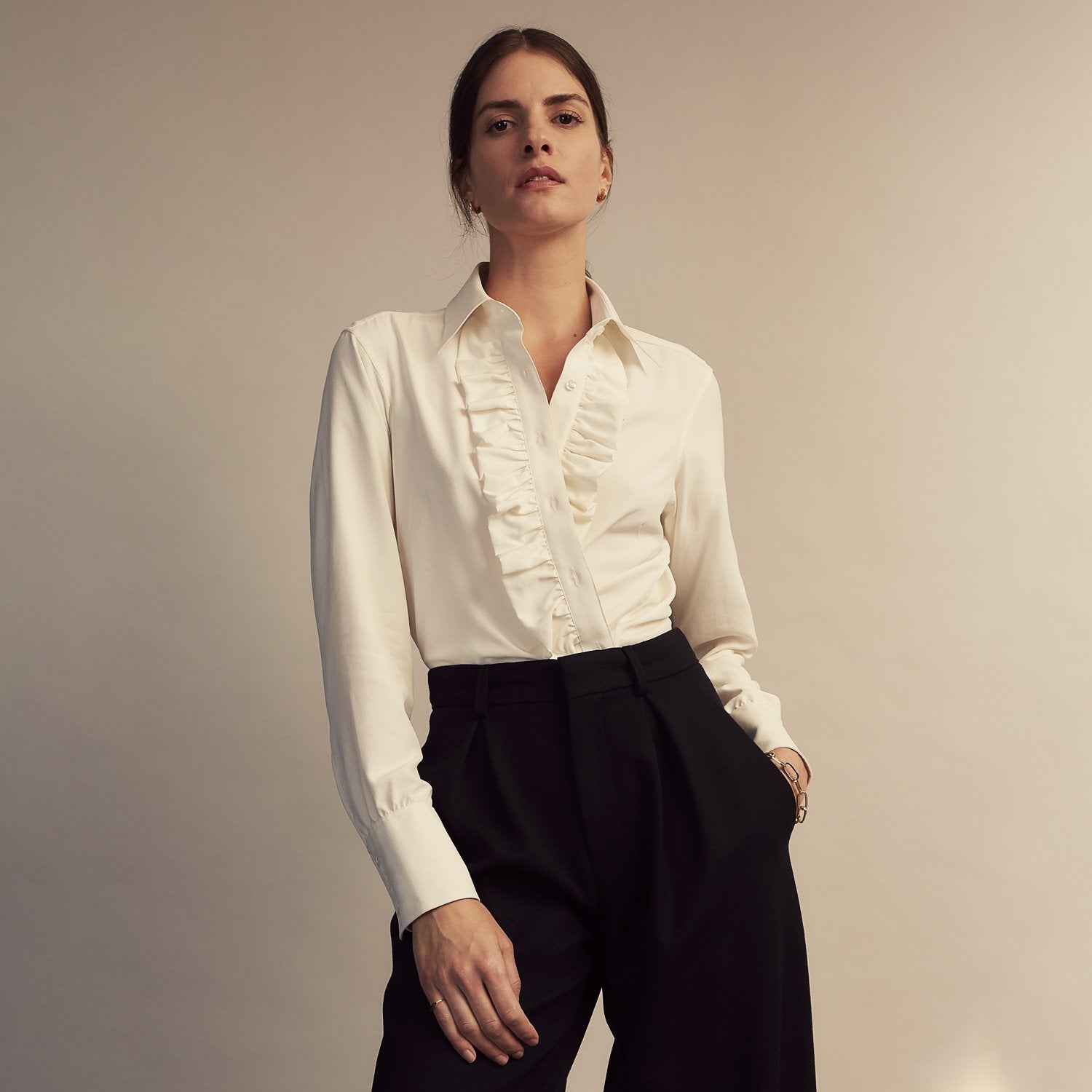 View 4 of product The Turnbull & Asser Turnbull and The Deck Cream Silk Romantic Shirt features long sleeves, a pointed collar, and elegant front ruffles, shown against a plain light gray background.