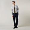 View 1 of product A man stands against a light background, wearing a Turnbull & Asser Yellow and Blue Fancy Check Regular Fit Shirt with T&A Collar, a patterned tie, dark dress pants, and black shoes. He faces forward with hands in pockets and a neutral expression.