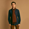 View 1 of product A man stands against a beige background wearing a navy long-sleeve shirt, brown pants, and a Turnbull & Asser Orange Multi Shepherd Check Cashmere Scarf draped around his neck. He faces forward with a neutral expression.
