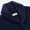View 2 of product The Turnbull & Asser Navy Shawl Collar Cashmere Cardigan features a chunky knit, ribbed texture, button front, and two pockets—a luxurious piece laid flat on a white background for warmth and style.