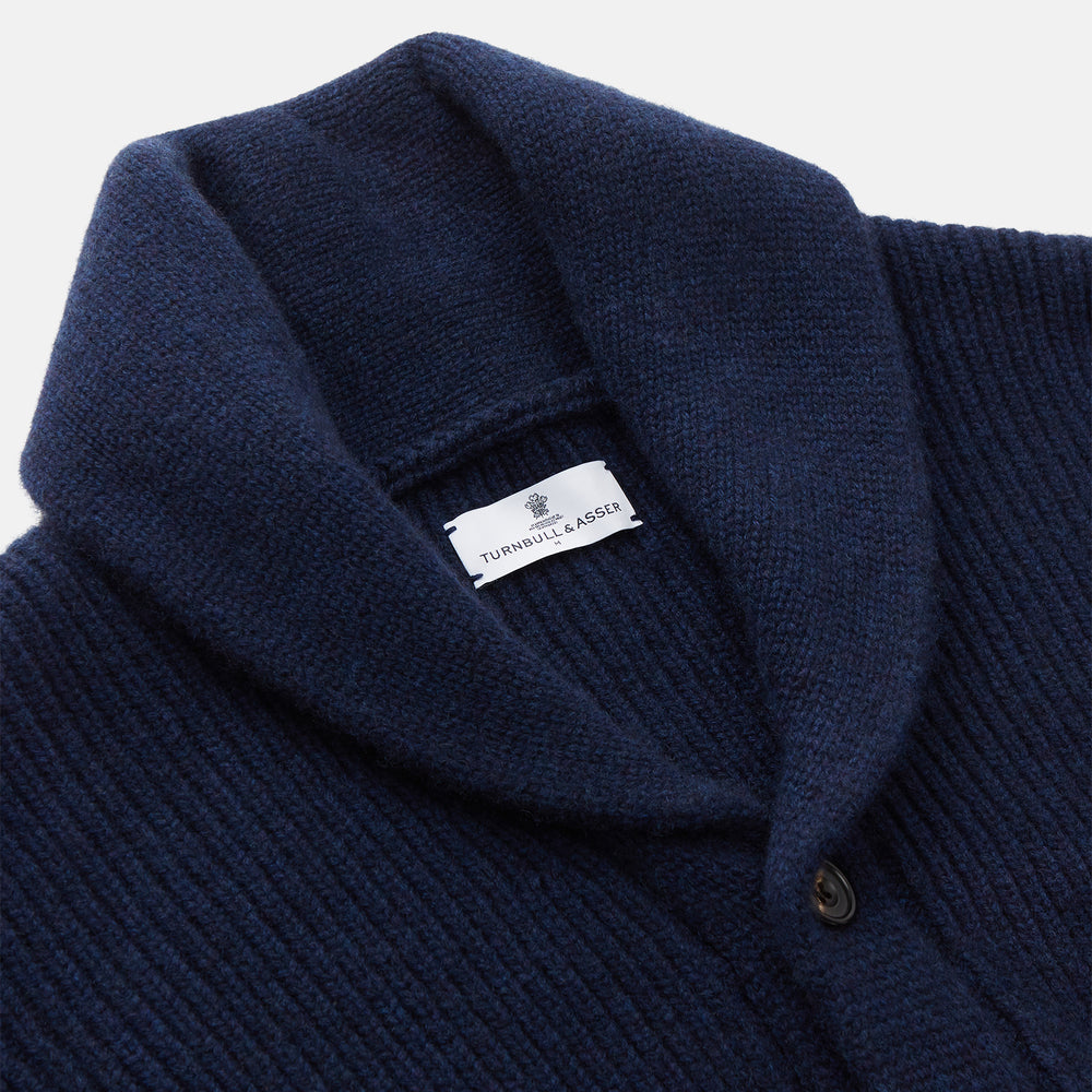 The Turnbull & Asser Navy Shawl Collar Cashmere Cardigan features a chunky knit, ribbed texture, button front, and two pockets—a luxurious piece laid flat on a white background for warmth and style.