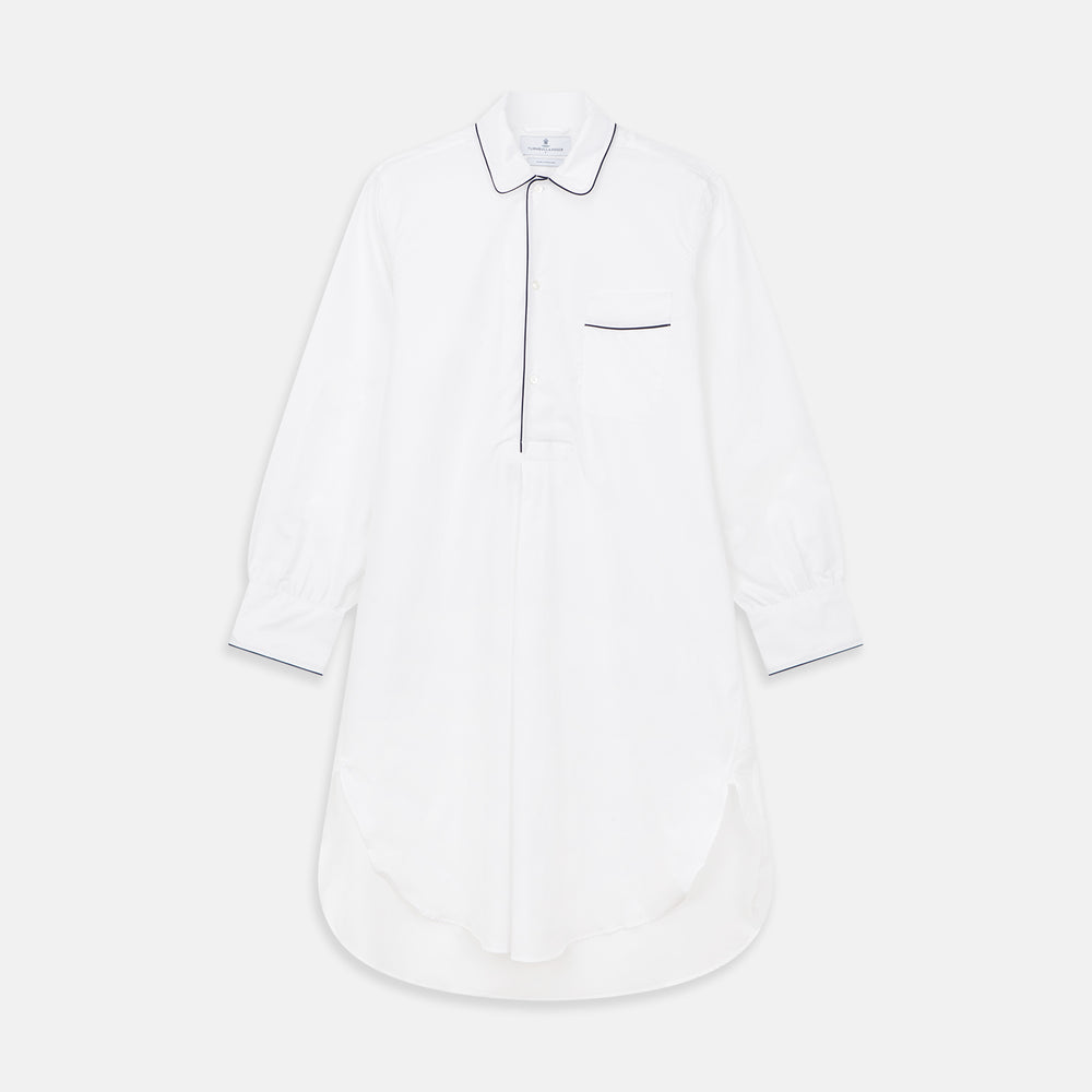 The Turnbull & Asser White Piped Cotton Nightshirt features black piping on the collar, chest pocket, and cuffs, plus a curved hem and loose-fitting sleeves gathered at the wrists for a classic look.